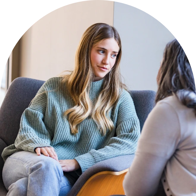 Young woman sitting on couch speaking to older woman