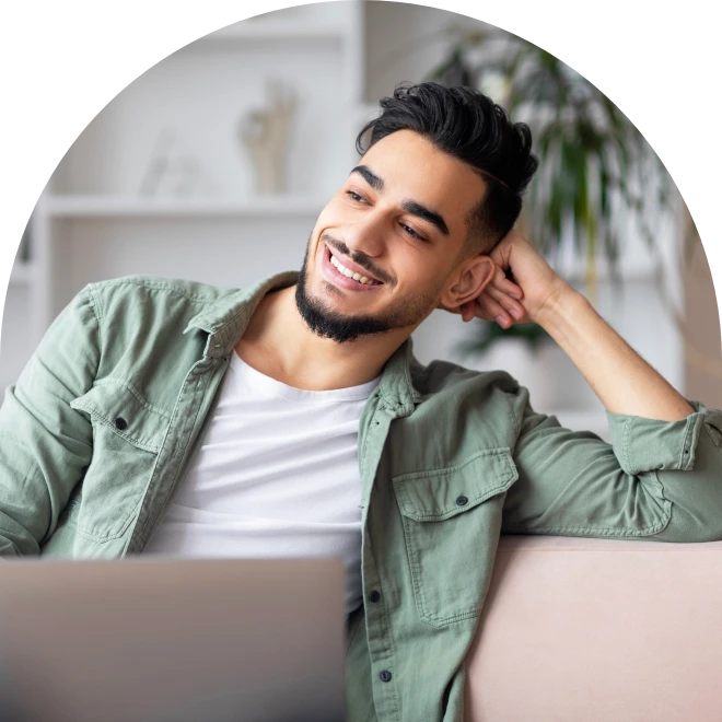Man sitting on couch, wearing white shirt and green long sleeve shirt