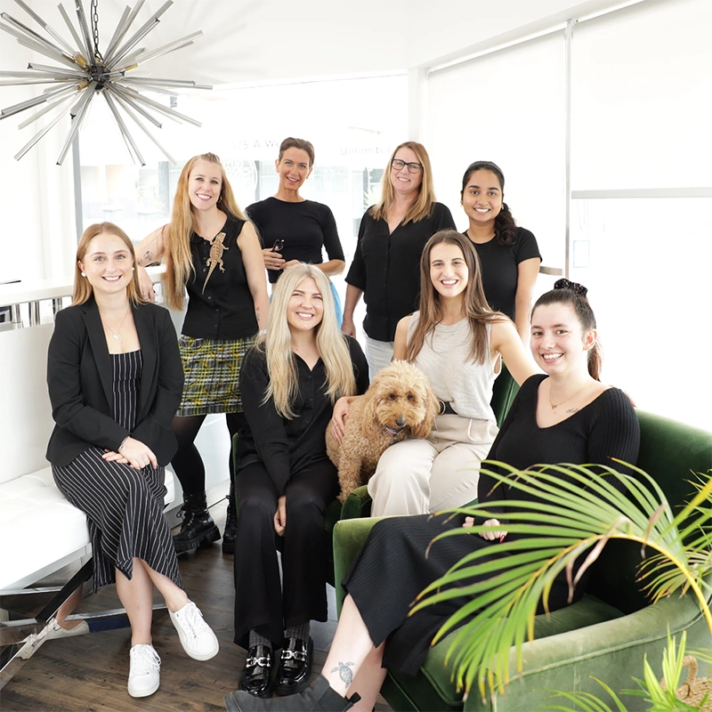 8 women standing and sitting in a group in the brightly lit Acacia Psychology office